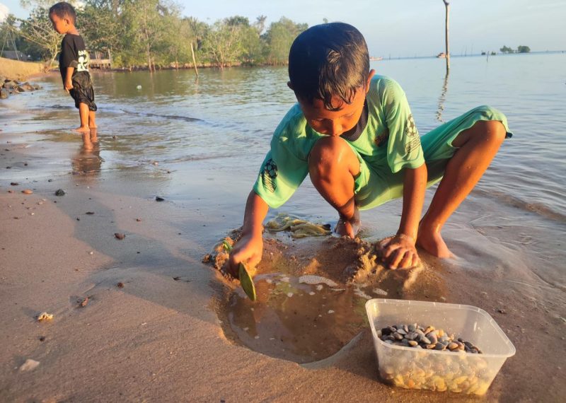 Potret anak laki-laki bernama M. Qadaffa saat mencari remis di pantai (Foto : Zonamu/Imam)