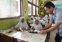 Pegawai PT Timah saat memberikan makanan bergizi gratis kepada pelajar sekolah dasar di Kabupaten Bangka Tengah | Foto: Zonamu/Humas PT. Timah