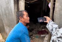 Seorang warga saat menunjukan korban tertimpa reruntuhan tembok pembantas (Foto : Zonamu/Wandi)