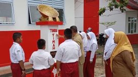 Guru SDN 010 Singkep saat memberikan penjelasan tentang tugu timah kepada para siswa (Foto : Zonamu/Wandi)