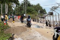 Potert ketika warga hendak melintas di jalan yang rusak akibat abrasi pantai (Foto : Zonamu/Wandi)