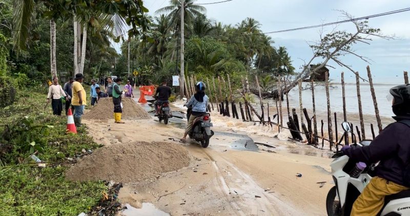 Potert ketika warga hendak melintas di jalan yang rusak akibat abrasi pantai (Foto : Zonamu/Wandi)