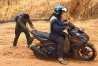 Salah seorang warga saat mendorong motor karena kondisi jalan yang licin (Foto : Zonamu/Paino)