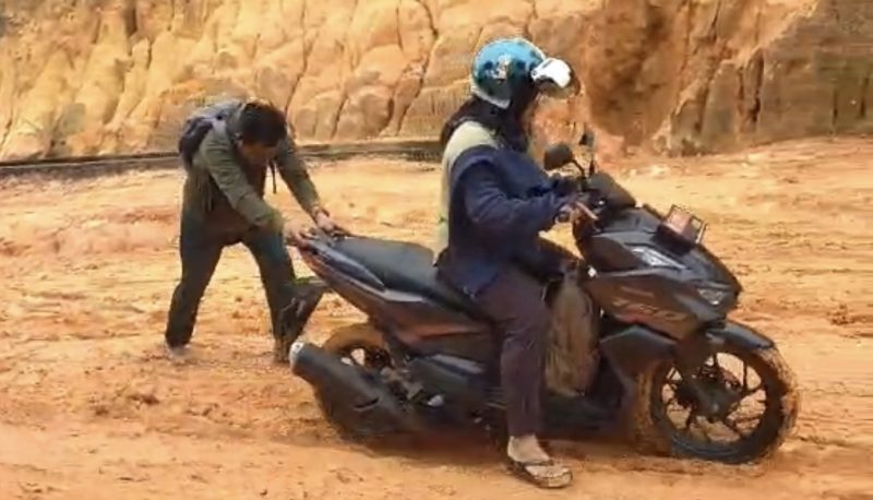 Salah seorang warga saat mendorong motor karena kondisi jalan yang licin (Foto : Zonamu/Paino)