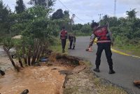 Personil Polres Lingga beberapa waktu lalu saat melakukan police line di jalan raya yang terkikis akibat abrasi pantai (Foto : Zonamu/Ist)