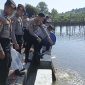 Personil Polres Lingga saat melakukan penebaran benih ikan nila (Foto : Zonamu/Wandi)
