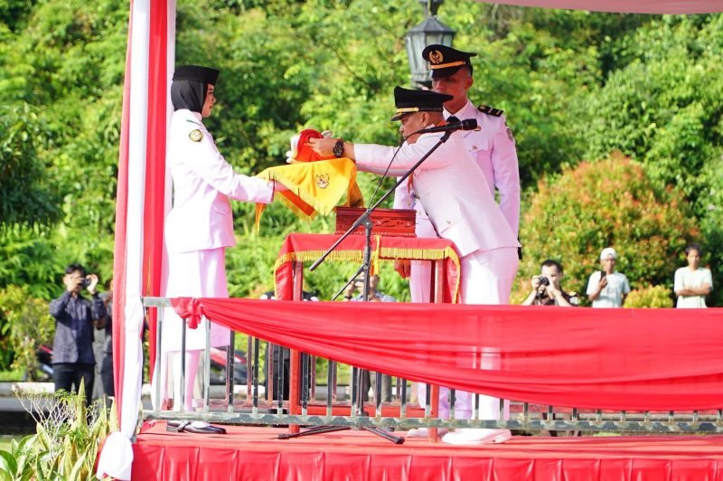 Bupati Lingga saat menyerahkan Bendera Merah Putih kepada Paski untuk dikibarkan | Foto : Zonamu/Diskominfo Lingga 
